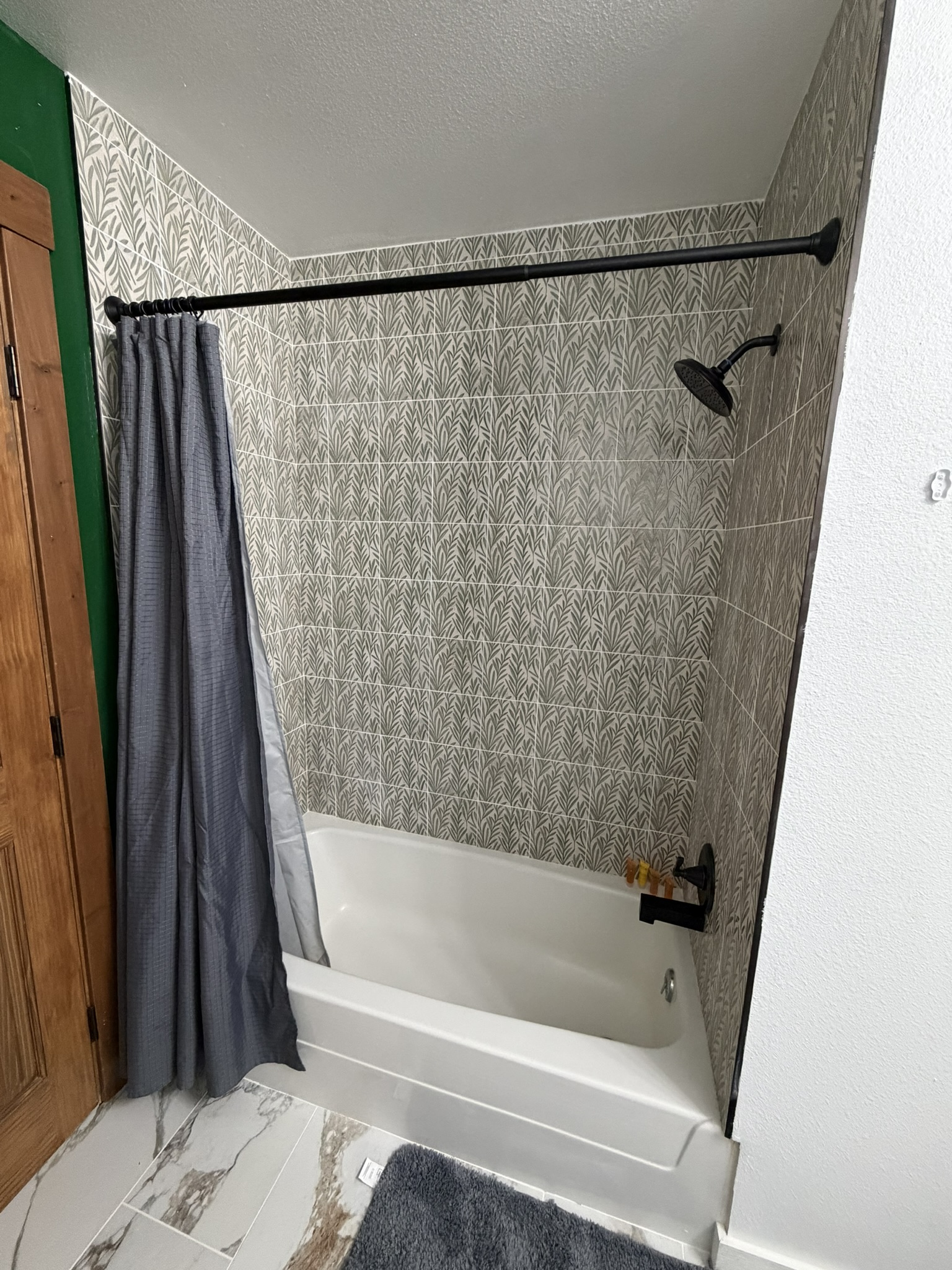 Renovated bathtub and shower with botanical tile and matte-black fixtures